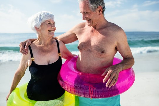 Senior couple in inflatable ring standing on beach