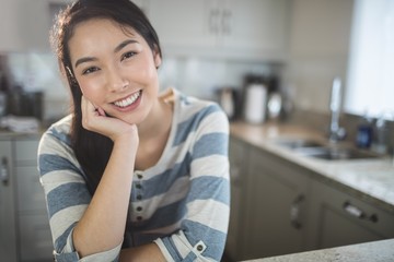 Portrait of happy woman sitting in kitchen