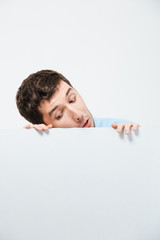 Young man peeking from blank board