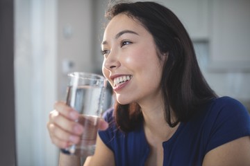 Young woman drinking a glass of water in kitchen