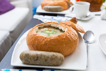 Easter traditional polish breakfast with white borsch soup in bread bowl, eggs and white sausages