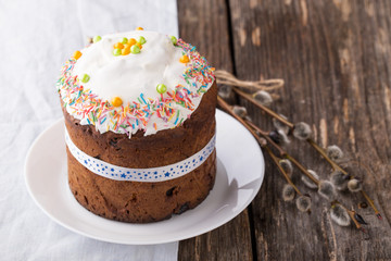 Traditional russian easter cake Kulich on white plate with willow branch on wooden background