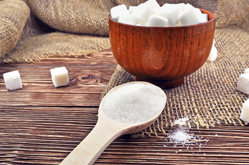 Wooden spoon and a sugar bowl with sugar on the table