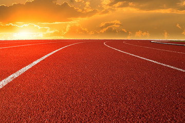 Fototapeta premium Athletics Stadium Running track curve and sunlight on orange sky