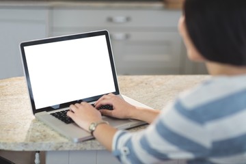 Woman using a laptop in the kitchen