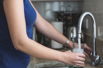 Close-up of woman washing a glass in kitchen sink