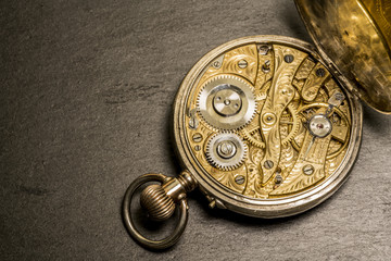 Offenes Uhrwerk einer alten Taschenuhr aus dem 19. Jahrhundert auf schwarzem Grund