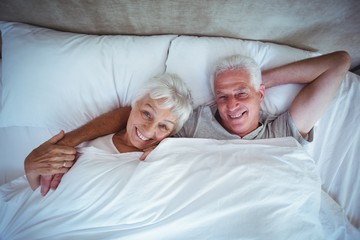 Happy senior man with wife lying on bed