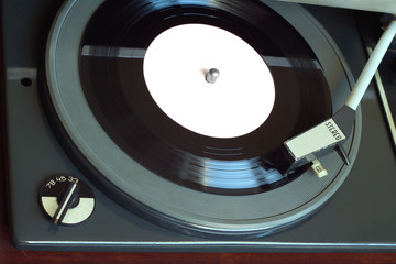Old vintage record player playing vinyl record with pink label. Horizontal top view closeup