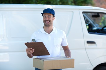 Smiling delivery man with clipboard and cardboard box 