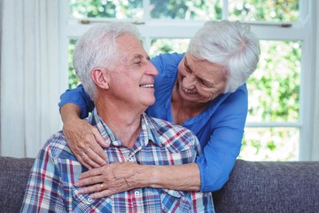 Cheerful wife embracing while looking at senior man