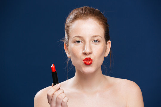 Young woman holding lipstick