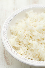 boiled rice on white bowl on white wooden background