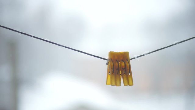 Four clothes pegs on a rope in the snow. 