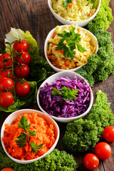 Composition with four vegetable salad bowls on wooden table