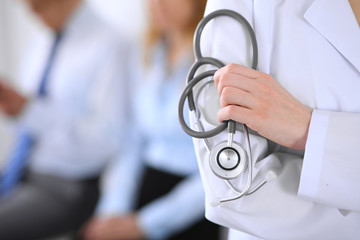 Doctor holding a stethoscope in his hands , the patient on the background