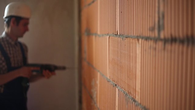 Worker drills hole in wall bokeh