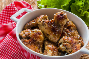 Roasted chicken wings in white baking dish. Cooked with sauce from mustard, honey and soy sauce.
