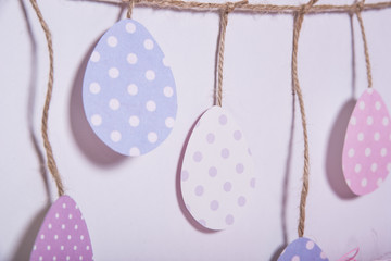 Happy Easter! Colorful Easter eggs hanging on a rope on a white background.