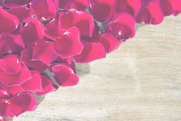 Red roses petals on wooden background.