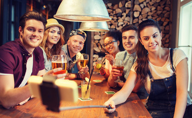 friends with smartphone on selfie stick at bar