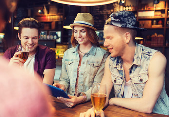 happy friends with tablet pc and drinks at bar