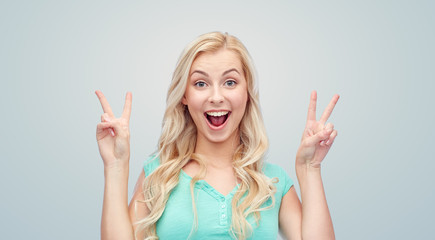 smiling young woman or teenage girl showing peace