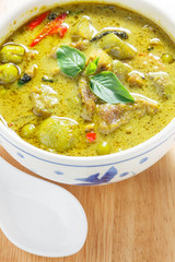 green curry and white spoon on wood background.