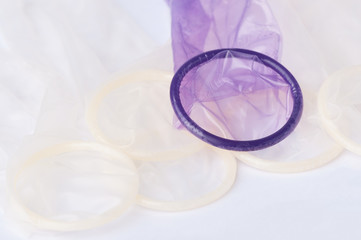 Fototapeta na wymiar Unrolled latex condoms on white background