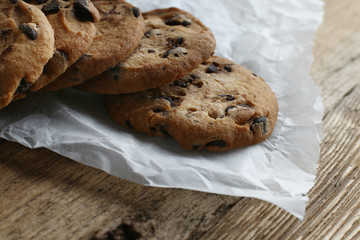 Cookies with chocolate chip on parchment paper napkin on wooden background