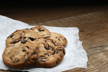 Cookies with chocolate chip on parchment paper napkin on wooden background