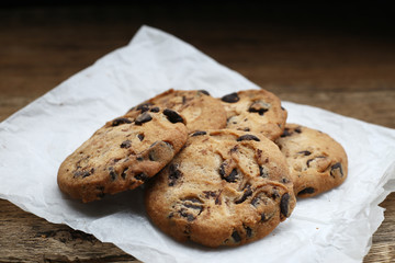 Cookies with chocolate chip on parchment paper napkin on wooden background
