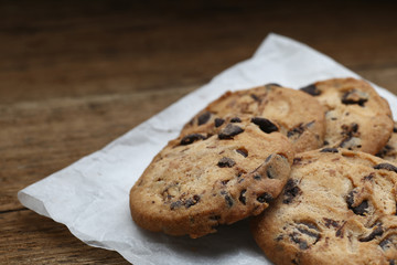 Cookies with chocolate chip on parchment paper napkin on wooden background