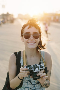 USA, New York, Coney Island, smiling young woman taking photos at sunset