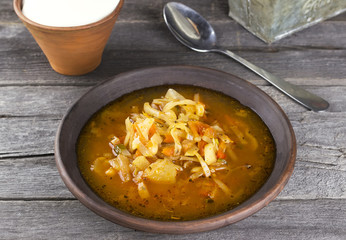 Russian cabbage soup in clay plate on a dark wooden background