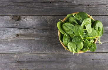 Spinach leaves in bowl on dark wooden background