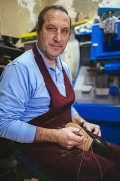 Portrait of shoemaker sewing a shoe in his workshop