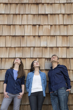 Group picture of three creative business people in front of wood shingle paneling