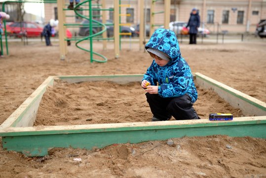 Little Boy Plays In A Sandbox On Playground