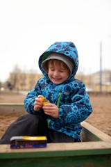 Little boy plays in a sandbox on playground