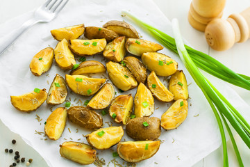 Crispy baked potato wedges on  parchment paper, vegetarian food, top view