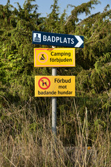 Obraz premium Swedish signs which indicate the direction to a baseplate, that camping is not allowed and dogs are not allowed to have a swim
