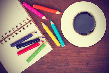 vintage open book and color pencil and a cup of coffee on wooden