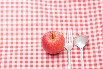 Red apple ,spoon and fork on table napkin