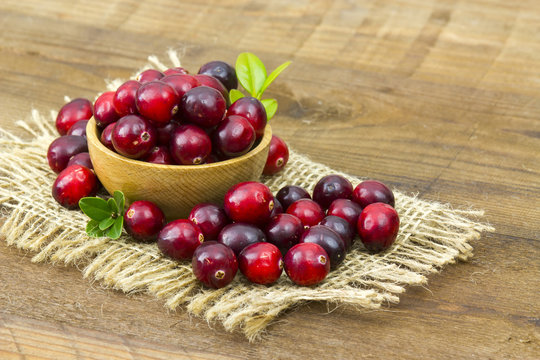 Cranberries in wooden bowl on wooden background