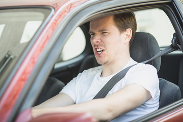 Wütender junger Mann sitzt im Auto