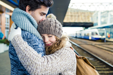 Smiling young couple embracing on station platform