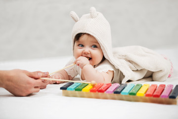 Baby girl playing xylophone toy on blanket at home © Wrangler