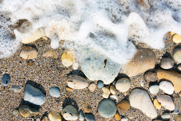 sassi vari colori sulla sabbia in riva al mare levigati bagnati dalle onde