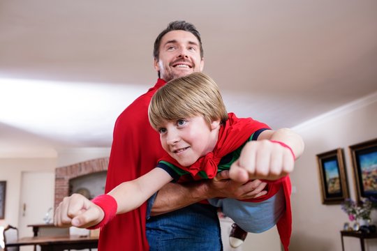 Father and son pretending to be superhero in living room